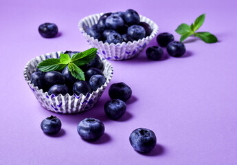 Juicy, fresh blueberries in paper forms on a purple background. Snack. 