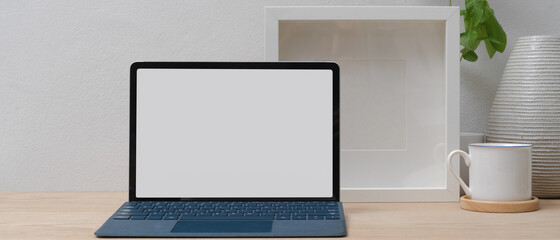 Modern home office with mock up tablet with keyboard, coffee cup and decorations on wooden table