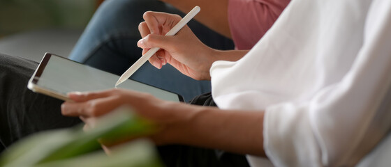 Female worker writing on mock up tablet while meeting with her colleague