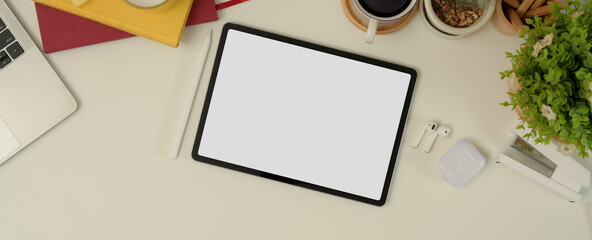 Mock up tablet on working desk with notebooks, laptop, stationery, supplies and decoration