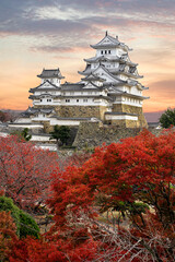 Himeji Castle and red maple leaves in evening sunlight and twilight sky in Himeji city, Japan.