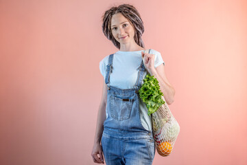 Modern woman in jeans is carrying a string bag with purchases. Concept of eco-friendly behavior,...