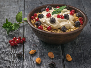Almonds and berries and a bowl of granola and yogurt on the table.