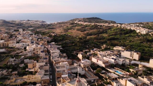 Xaghra Parish Church aerial pan shot church reveal fly backward. Gozo, Malta in summer hot day.