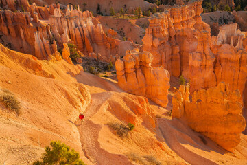 A hiker on a trail in Bryce Canyon National Park, Utah. The park features a collection of giant natural amphitheaters and is distinctive due to geological structures called hoodoos.