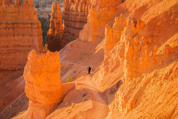 A photographer on a trail in Bryce Canyon National Park, Utah. The park features a collection of giant natural amphitheaters and is distinctive due to geological structures called hoodoos.
