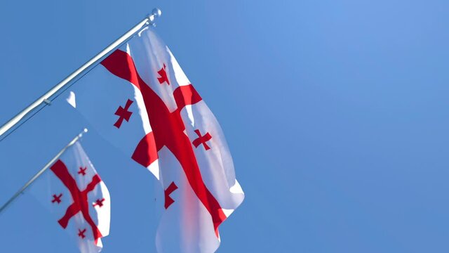 The national flag of Georgia is flying in the wind against a blue sky