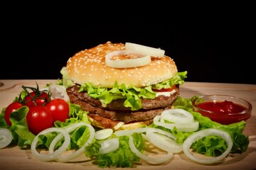 Sandwich with onions, meat and herbs and tomatoes on a dark background