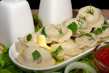 Boiled dumplings with butter and herbs on a white plate