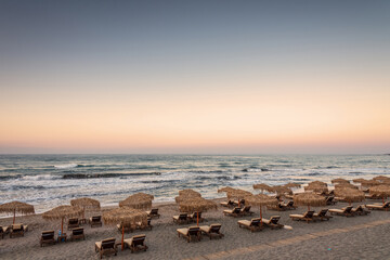 Sun loungers with umbrella on the beach, sunrise.