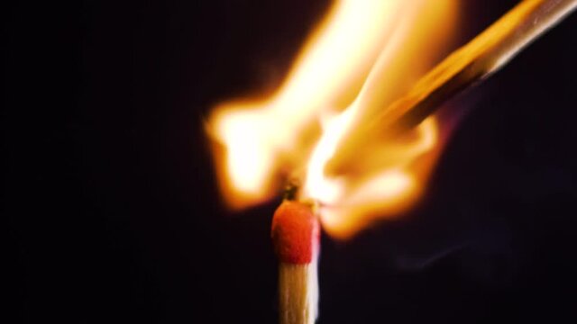 One match is lit by another on a set with one light and black Background - Slowmotion