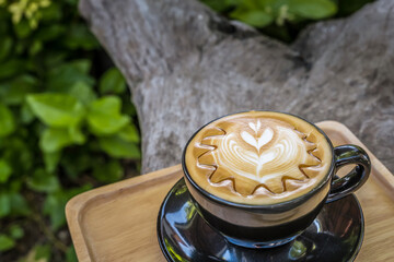 Gray cup of fresh cappuccino with latte art on the wooden table background.