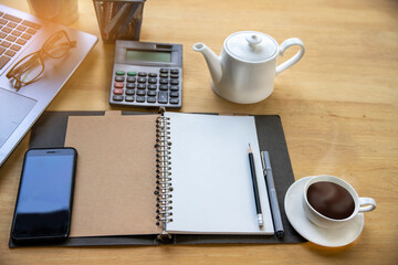 Wood office desk table with smartphone with blank screen, laptop computer, cup of coffee and supplies