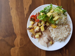 Fish with rice and pineapple salad on a wooden background