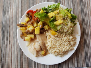 A Fish dish with rice and salad with pineapple