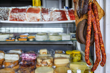 Cheeses on display and sausages hanging at a stall at an outdoor farmer's market in old town Kotor, Montenegro