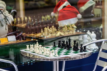 A table with a chess board and figures on the side of the street at a board game shop