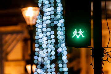 Pedestrian semaphore with green light and defocused Christmas tree lights in the background