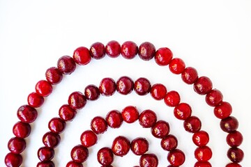 Red cherry ripe juicy is laid out in a spiral on a white background.