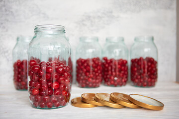 Not closed glass jars with cherries, prepared for canning with tin screw lids