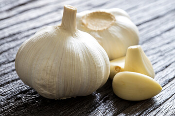 Raw Garlic Bulb and Cloves on dark wooden background..