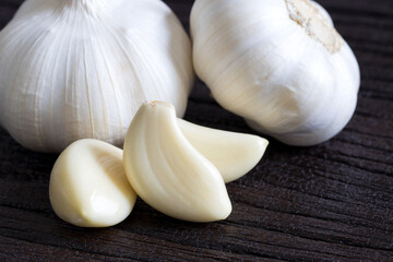 Raw garlic cloves and bulb on dark wooden background