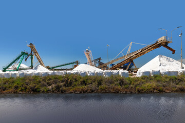 Close up a number of conveyor belts use to process raw salt in southern france, against a solid blue summer sky