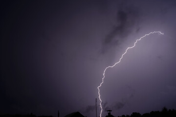 A bright flash of lightning against the dark purple night storm sky>