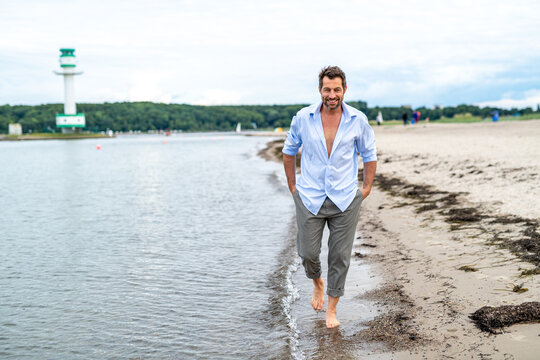 l&auml;ssiger Mann geht am Strand spazieren