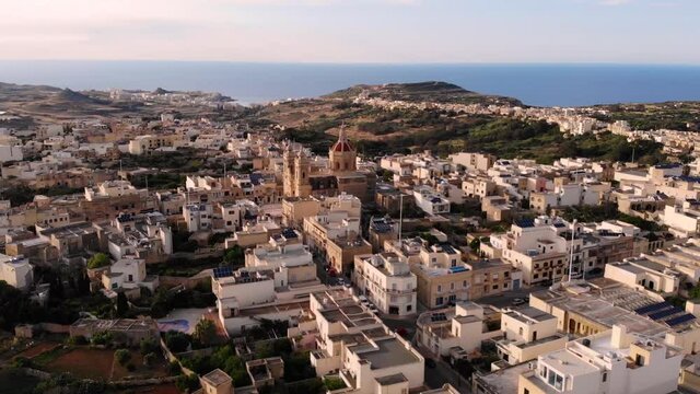 Baroco church in Gozo aerial drone pan fly straight to shot of Xaghra Parish Church, scenery of beautiful mediterranean town.
