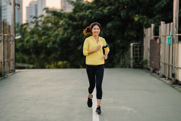 Beautiful young Asia athlete lady running exercises work out in urban environment. Japanese teen girl wearing sports clothes on walkway bridge in early morning. Lifestyle active sporty in city.