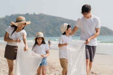Asian young happy family activists collecting plastic waste and walking on beach. Asia volunteers...