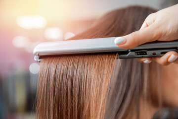 Keratin recovery and treatment with professional iron tool. Laminated long dark shiny hair closeup