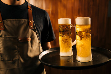 Waiter with two cold beer mugs on the tray