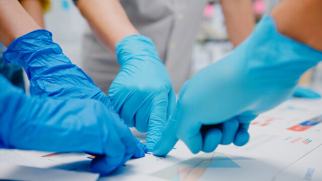 Asia businesspeople discussing business brainstorm meeting together share data, wearing face mask and glove back at work in new normal office. Lifestyle and social distancing at after coronavirus.