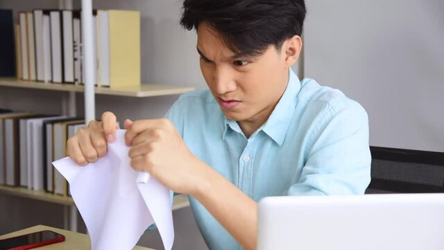 Asian business man in blue shirt outfit get angry and furious from getting fired and become unemployed immediately at modern office workplace. Unemployment concept.