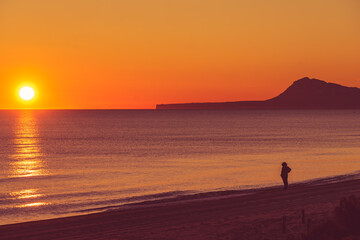 Naklejka na ściany i meble Person silhouette on beach enjoy sunrise