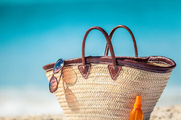 Summer vacation beach bag with sunglasses and sunscreen suntan bottle for solar protection skin care womens travel accessories for sun vacations.