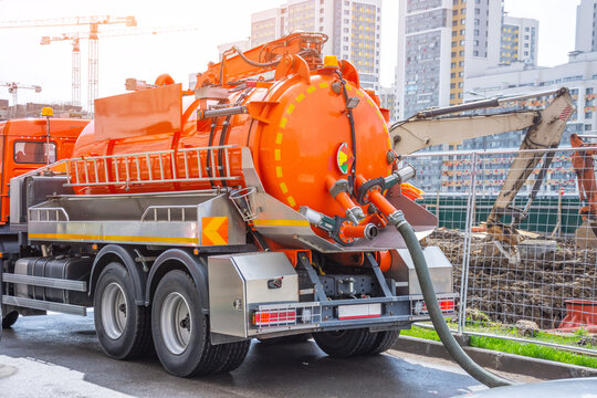 Pumping water from sewage canals during the construction of roads in the city. Truck with orange water tank.