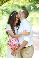 Beautiful couple in love. Loving couple in the garden among the flowers. Lovers newlyweds. Just married. Beautiful bride and groom are hugging in the park. Wedding portrait of lovers newlyweds