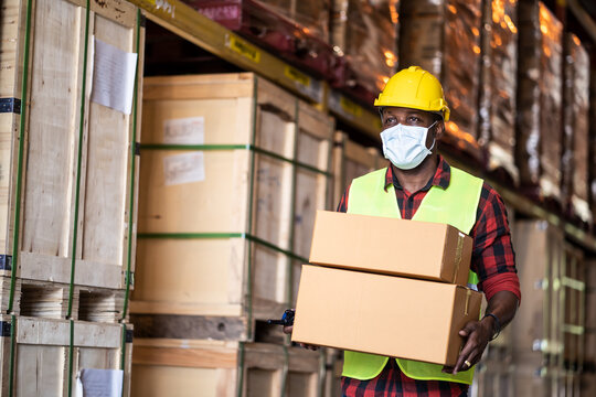 Black male workers wearing protective face mask working in warehouse.