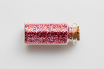 party, decoration and holidays concept - red glitters in small glass bottle with cork stopper over...