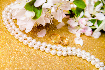 Obraz na płótnie Canvas Gold wedding rings and Apple blossoms on a Golden background 