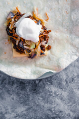plant-based food, vegan burrito wrap getting prepared with beans in spicy sauce dairy-free cheese and coleslaw with coconut yoghurt
