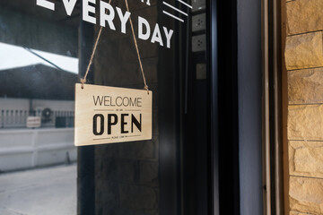 Barber in barber shop turning Welcome open sign front glass door store