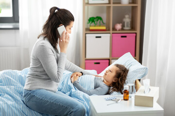 family, health and people concept - ill daughter and mother with smartphone calling doctor at home