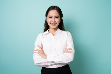 Portrait of young asian woman crossing arms and smile on blue background.