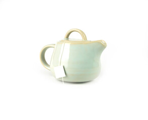 Ivory color ceramic teapot with a tea bag inside and white label isolated on a white background, Asian food concept with copy space..