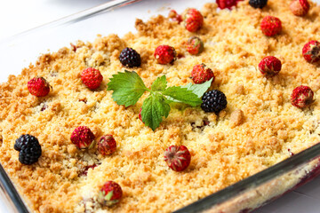 Ruddy crumble with field strawberries, decorated with a sprig of mint