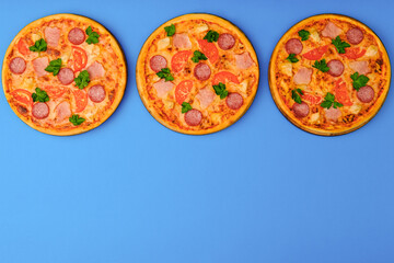 Three pizzas on the blue azure background. Pizza isolated. Banner with copy space for text or logo. Italian cuisine.